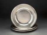 une assiette en argent posée au sommet d'une pile d'assiettes en argent