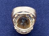 a gold ring with a stone inside of it on a blue surface