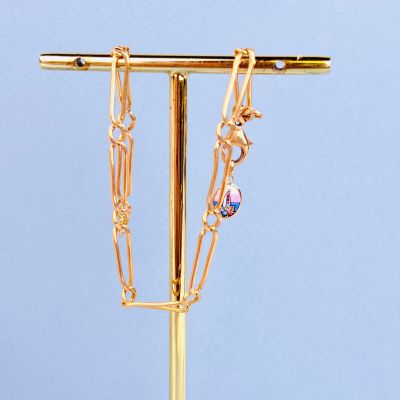 un collier plaqué or posé sur un socle avec un fond bleu