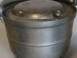 a metal pot with a handle sitting on a table