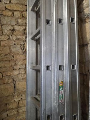 une échelle métallique appuyée contre un mur de briques