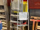 un homme debout à côté d'une pile d'échelles dans un entrepôt