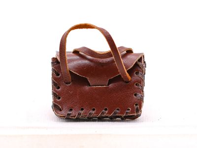 un petit sac à main marron muni d'une anse, posé sur une surface blanche