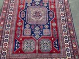 a red, blue and white rug sitting on top of a cement floor