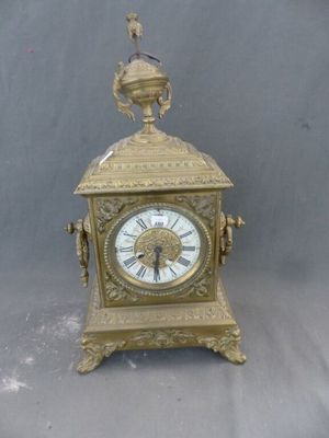 une horloge en or surmontée d'un oiseau