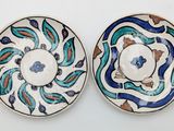 two plates with blue and green designs on them on a white surface
