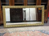 un grand miroir posé par terre devant une bibliothèque