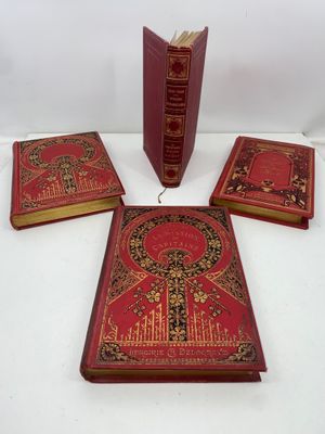 trois livres rouges ornés de bordures dorées et de motifs décoratifs