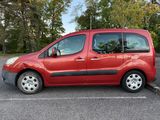 a red van parked in a parking lot with trees in the background