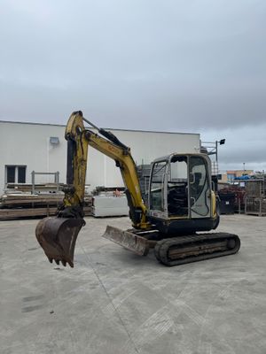 an image of a small excavator in a parking lot