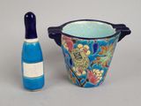 a blue vase and a bottle of wine next to each other