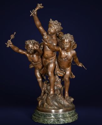 une statue en bronze représentant trois chérubins sur un socle, avec un oiseau en plein vol