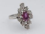 a close up of a ring with a ruby stone surrounded by diamonds