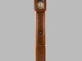 une grande horloge de parquet en bois sur fond gris