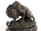 statue d'un lion perché sur un rocher, tenant un serpent dans la gueule