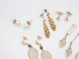 several pairs of earrings and rings are arranged on a white surface
