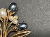 a black and white brooch with pearls on it