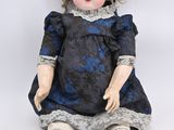 doll sitting on the floor wearing a blue dress and brown shoes