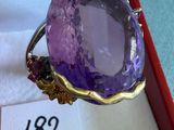 une photo d'une bague en pierre violette dans un écrin rouge
