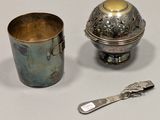 une tasse en argent et une cuillère posées l'une à côté de l'autre