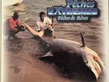 two men standing next to a dead shark in the water