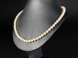 a white pearl necklace on a mannequin with a black background