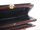 someone is holding a brown purse with a gold handle