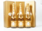 trois bouteilles de champagne dans un coffret doré, posées sur un fond blanc