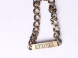 bracelet à chaîne en argent orné d'une plaque portant un nom, sur un fond blanc