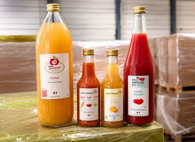 Plusieurs bouteilles de jus sont alignées sur une palette dans un entrepôt