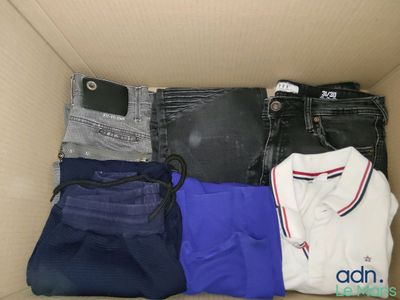 une boîte en carton remplie de vêtements divers et d'un téléphone portable