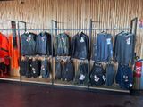 many jackets and pants hanging on a rack in a store