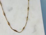 une photo d'un collier en or posé sur une surface en marbre