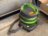 a green and black vacuum on the ground next to a box of boxes
