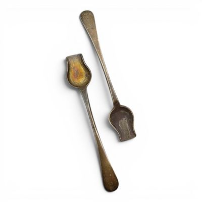 two spoons and a spoon rest next to each other on a white surface