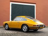 yellow porsche 911 parked in front of a building with a garage door