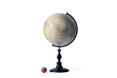 un petit globe terrestre posé sur un socle, avec une boule rouge