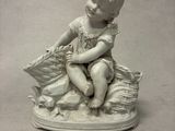 une petite statue représentant un garçon assis sur un oreiller