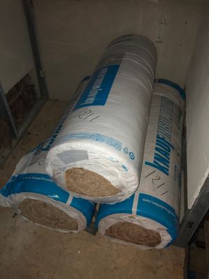 two rolls of insulation sitting on top of a floor next to a wall