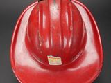 an old red hard hat sitting on top of a black table