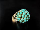 a close up of a ring with turquoise stones on a black surface