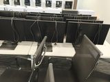 rows of computer monitors in a large room with desks and chairs
