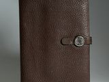 un gros plan d'un carnet en cuir marron muni d'un bouton sur la couverture