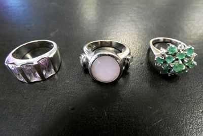 trois bagues différentes ornées de pierres vertes et blanches sur un fond noir