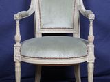 une vieille chaise dont l'assise est recouverte d'un tissu vert sur fond bleu