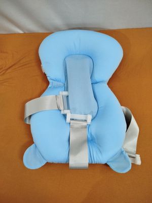 un siège bébé bleu posé sur un lit aux draps orange