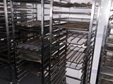 many racks with trays of food on them in the kitchen