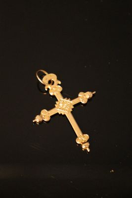 gold cross on a black surface with a black background