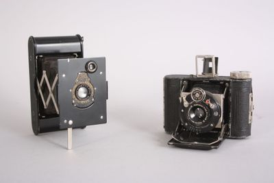 two old cameras sitting next to each other on a white surface