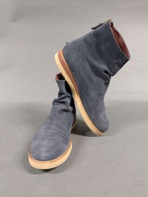 a pair of grey sued boots with brown soles on a grey background